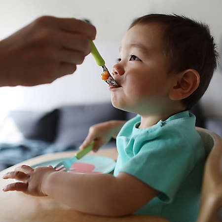 a small child is fed with a spoon