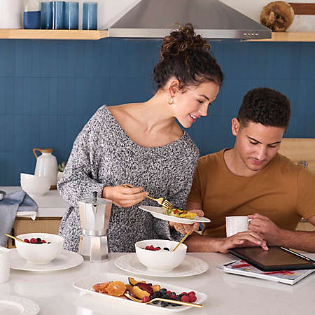 a couple looks at a tablet device over breakfast